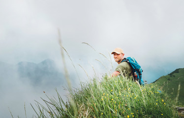 Wall Mural - happy backpacker man has a rest break enjoying cloudy valley bottom walking by the foggy cloudy weat