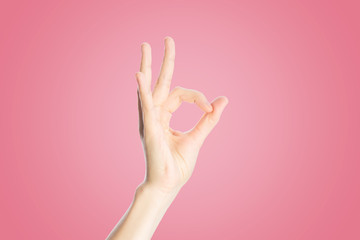 Wall Mural - Positive gesture on a pink background. Hand show okay sign, close up