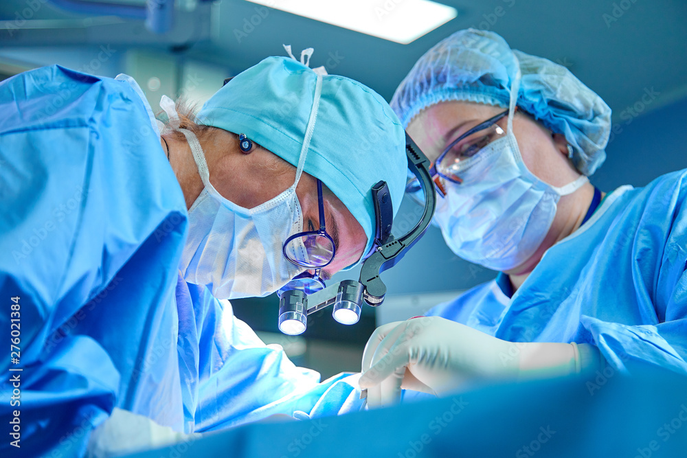 A surgeon's team in uniform performs an operation on a patient at a cardiac surgery clinic. Modern medicine, a professional team of surgeons, health. - obrazy, fototapety, plakaty 