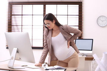 Poster - Young pregnant woman suffering from pain while working in office