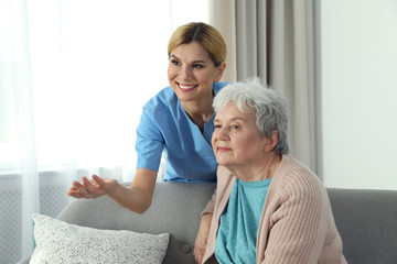 Wall Mural - Nurse with elderly woman indoors. Assisting senior people