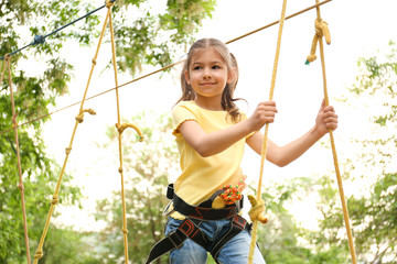 Wall Mural - Little girl climbing in adventure park. Summer camp