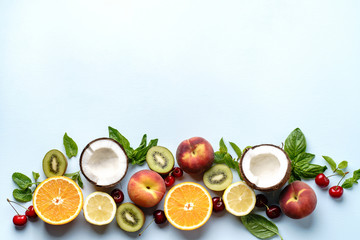 Summer vitamin food concept, various fruit and berries. Peach, kiwi, lemon, cherries, oranges creative flat lay on light blue background, top view, copy space