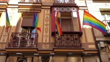 Rainbow LGBT Flag Waves Against Blue Sky In The City