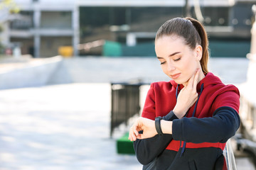 Sticker - Sporty young woman checking her pulse outdoors