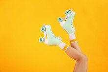 Legs Of Woman In Roller Skates On Color Background