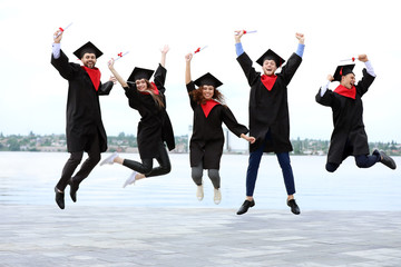 Sticker - Happy students in bachelor robes and with diplomas outdoors