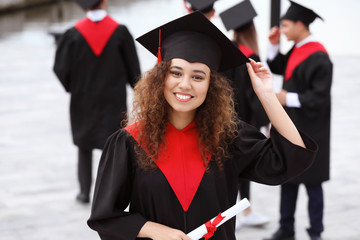 Sticker - Happy African-American student in bachelor robe and with diploma outdoors