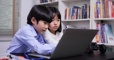 Little girl and boy using laptop to working together at library. Education and Teachnology concept.