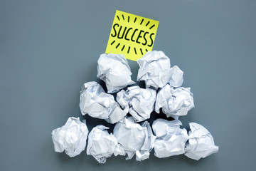 Success and failure in business. Pyramid from paper balls and memo stick on top.