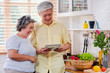 © weedezign - Asian senior couple using table computer to searching menu recipe and type of vegetable in kitchen at home.senior with technology lfiestyle.aging at home