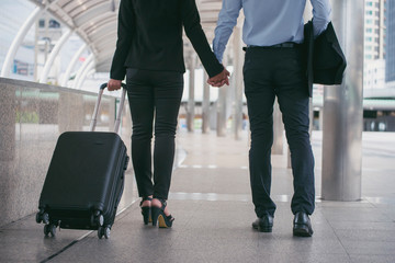 Business man and woman  Dragging suitcase luggage bag,walking to passenger boarding in Airport,travel to work.Asian tourist men and women  wearing black suit pull trolley bag. Business travel concept