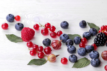 Wall Mural - Delicious berries in a bowl, currants, blackberries, blueberries, raspberries on a white wooden table. place for text. top view. frame