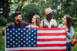 © Тарас Нагирняк - Happy  four students relaxing on nature with american flag, celebrating 4th july - Independence Day. After education.