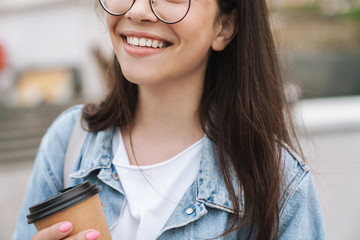 Sticker - Smiling young pretty woman student walking outdoors in green nature park drinking coffee.