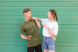 © bodnarphoto - Expressive amusing couple listening to music in headphones on a green background,young man and the girl sing and watch each other.Couple of friends listening to music on the background of a green wall