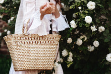 Street Fashion Details Of Elegant, Trendy Summer, Spring Outfit: Straw Wicker Basket Bag In Woman`s Hand. Copy, Empty Space For Text