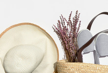 Summer Fashion Travel Vacation Concept. Women's Female Beachwear Hat Rattan Wicker Bag Canvas Striped Shoes Lavender Bouquet On White Background. Bright Sunlight Harsh Shadows. Creative Flat Lay