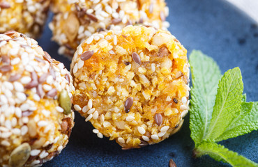 Energy ball cakes with dried apricots, sesame, linen, walnuts and dates on a blue ceramic plate, side view, close up.