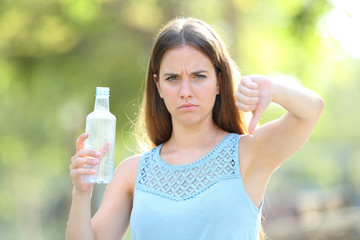  Angry woman holding a plastic bottle with thums down