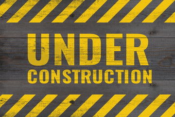 under construction warning message painted on aged wooden planks