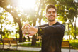 © Drobot Dean - Cheerful young sports fitness man standing in green park nature make stretching exercises for arms.