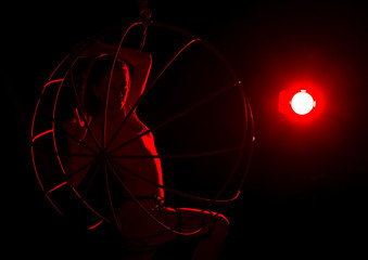 silhouette of sexy woman in red light on a dark background. leggy woman in a bodysuit with metal rings