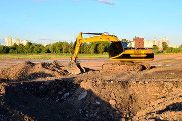 Wall Mural - Large tracked excavator digs the ground for the foundation and construction of a new building in the city. Road repair, asphalt replacement, renovating a section of a highway, bridge construction