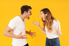 Photo Of Furious Aggressive Couple Man And Woman In Basic T-shirts Screaming At Each Other While Standing Face To Face