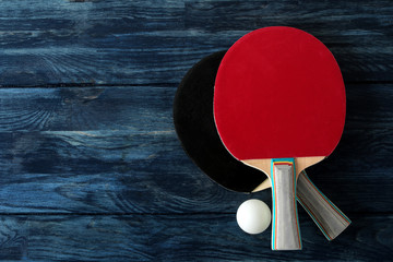 Wall Mural - Two ping pong rackets. Table tennis rackets and a ball on a blue wooden table. sport game. top view