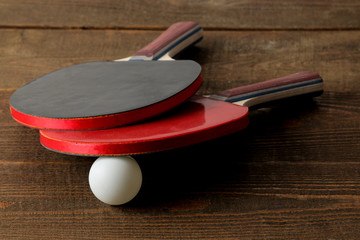 Wall Mural - Two ping pong rackets. Table tennis rackets and a ball on a brown wooden table. sport game.