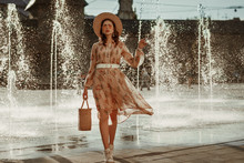 Outdoor Full Body Portrait Of Young Fashionable Woman Wearing Straw Hat, Pink Sunglasses, Stylish Dress, Holding Straw Wicker Basket Bag, Posing In Street Of European City. Copy, Empty Space 