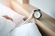 © BoszyArtis - Woman sleep on the bed turns off the alarm clock wake up at the morning, Selective focus.
