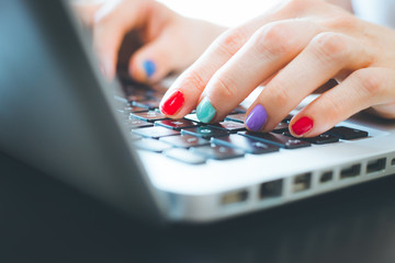 Home office or online shopping: Woman fingers with colorful nails are typing on a notebook keyboard
