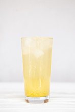 A Refreshing Summer Cocktail Of Yellow Color In A High Transparent Glass With Pineapple Slices On A White Background.