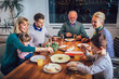 © Mediteraneo - Multi generation family enjoying meal around table at home
