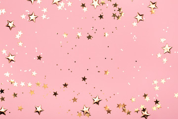 Wall Mural - Golden stars glitter on pink background. Festive holiday pastel backdrop.