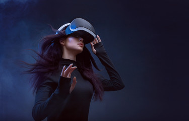 Wall Mural - beautiful woman with flowing hair in futuristic dress over dark background. girl in glasses of virtu