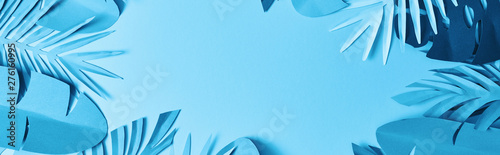 Fotomural frame of blue minimalistic paper cut palm leaves on blue background with copy sp