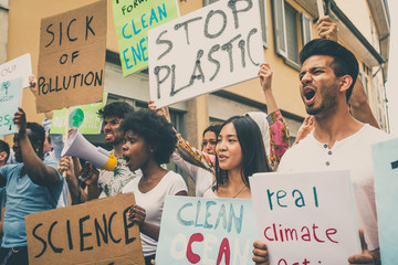 Public demonstration on the street against global warming and pollution. Group of multiethnic people making protest about climate change and plastic problems in the oceans