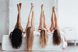 Different skin colors. Four young women with good body shape lying on the bed with their legs up