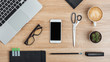 © Оlgart - Smartphone with empty screen, laptop, glasses, notepads, stationery, cactus and cup of coffee on the office desk. Top view.Mock up.