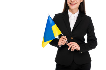 Wall Mural - cropped view of smiling businesswoman in black suit holding Ukrainian flag isolated on white