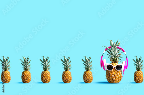 Fotomural One out unique pineapple wearing headphones on a solid color background