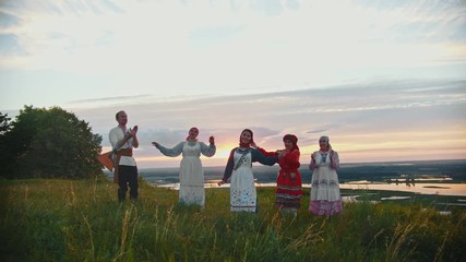 Wall Mural - Young people in russian traditional clothes having fun on the field - singing, dancing