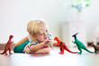 © famveldman - Child playing with toy dinosaurs. Kids toys.