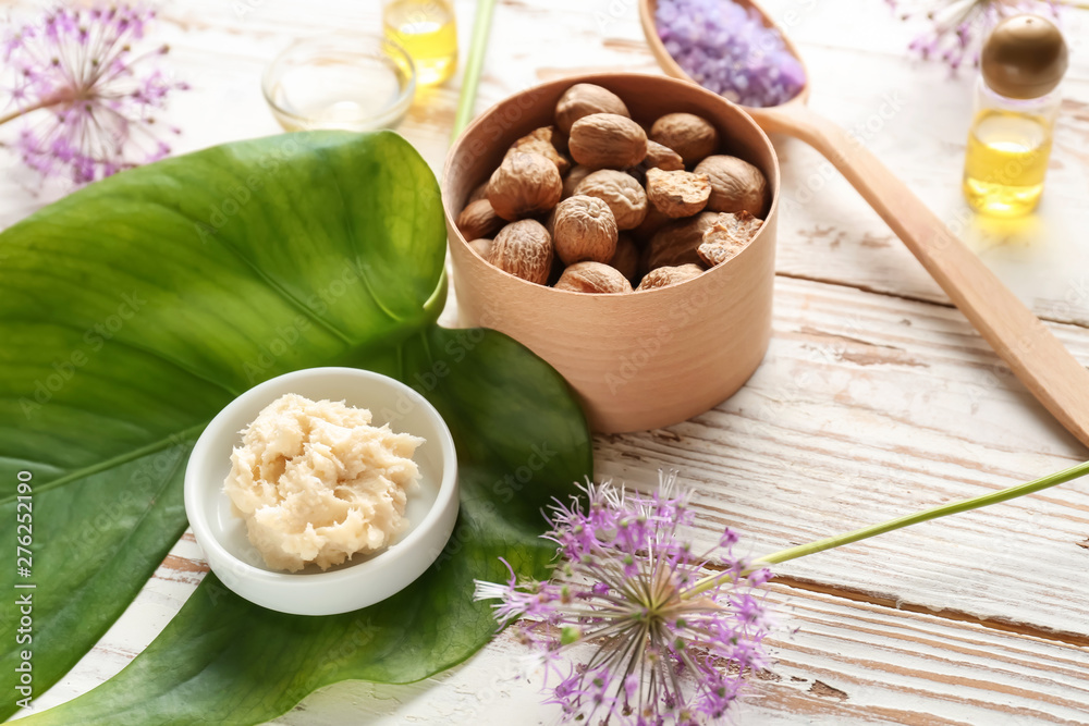 Shea butter with nuts on white wooden background