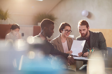 Multi-ethnic group of business people working in cafe lit by sunlight, copy space