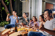 © DragonImages - Excited young people having pizza with wine when watching sport competition online in backyard