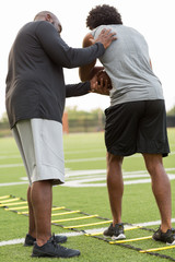 Wall Mural - American Football coach training a young athlete.